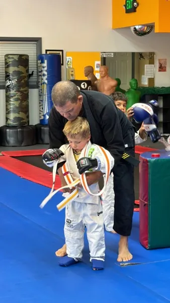 George Fujii holding a pad for a young student's kick