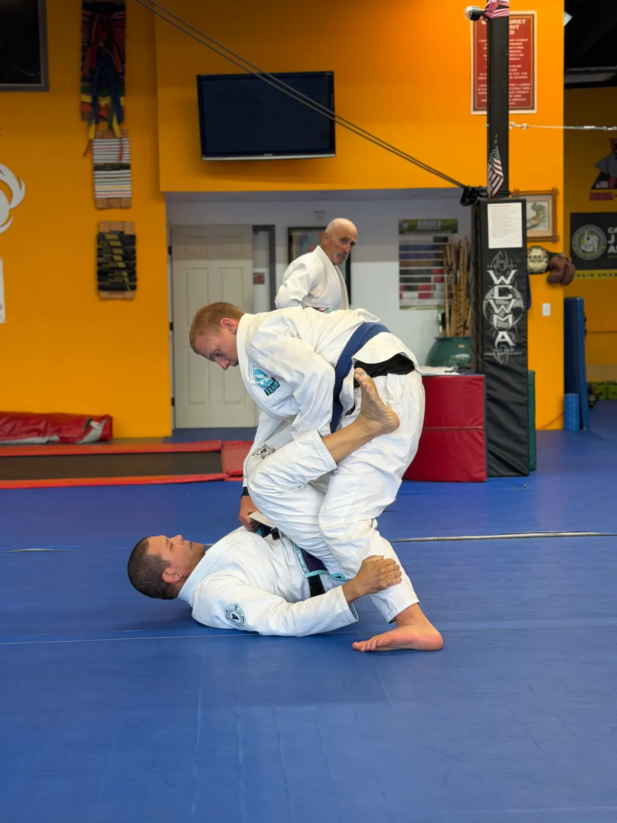 Adult student passing guard with a knee slice during Brazilian Jiu-Jitsu training at WCMA