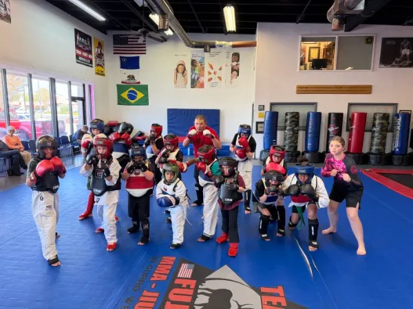 Kids lined up in full sparring gear with headgear and gloves at West Coast Martial Arts